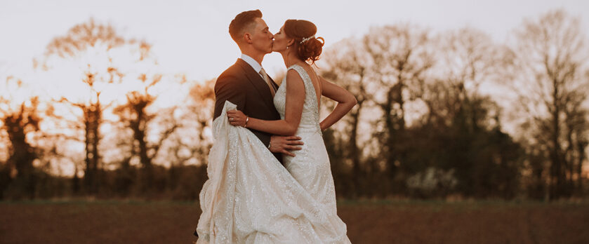 Bridge and groom kissing outside