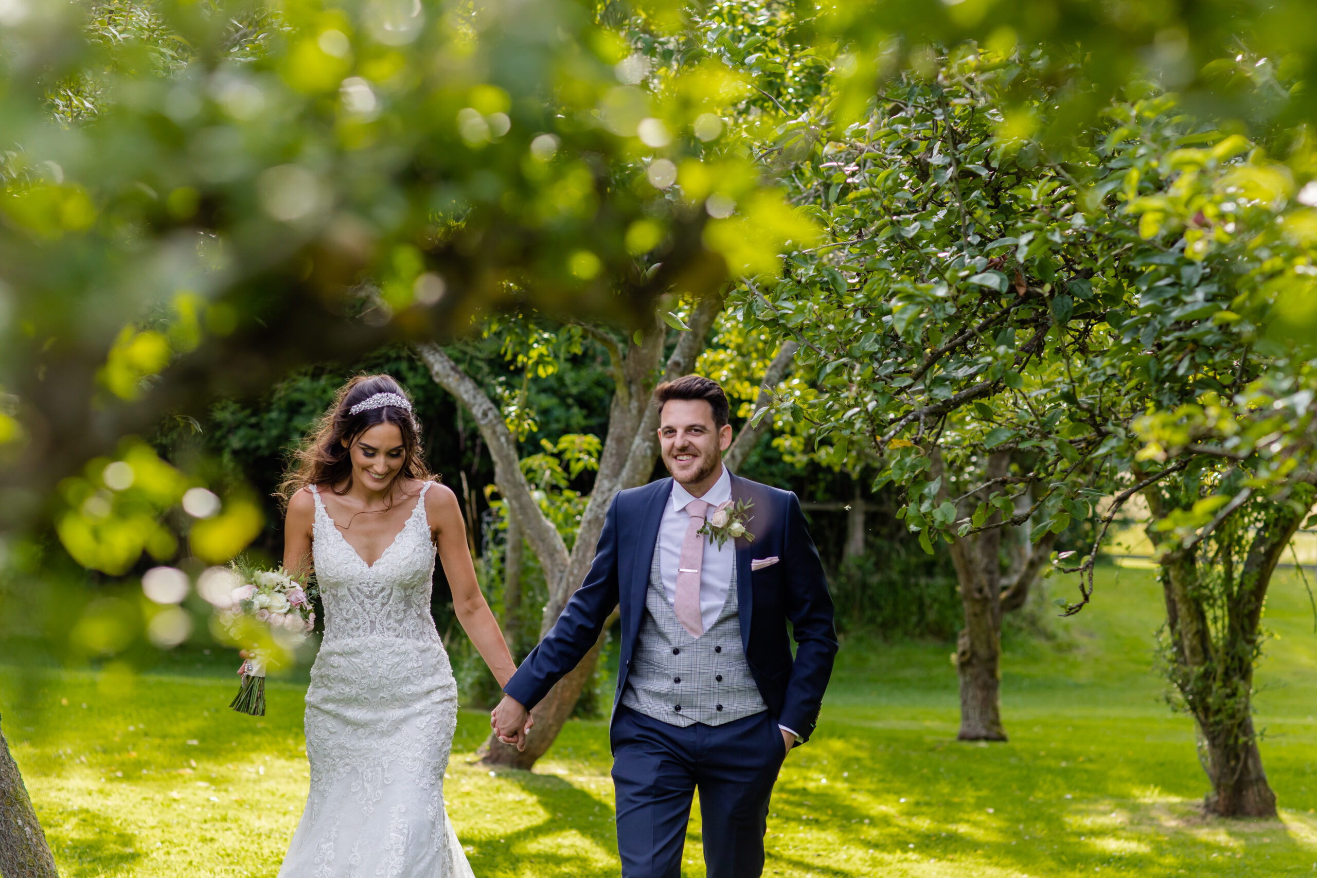A bride and groom smiling walking through the grounds of Essex barn wedding venue Colville Hall